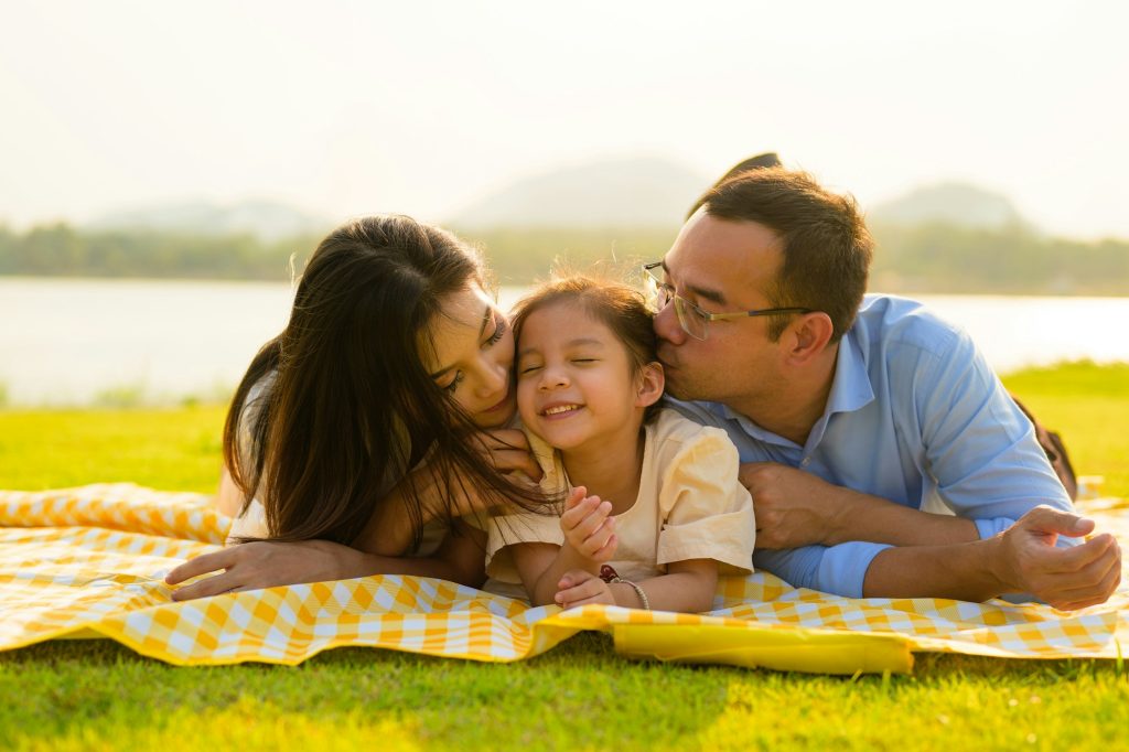 Happy family relaxing and resting in park together on weekend